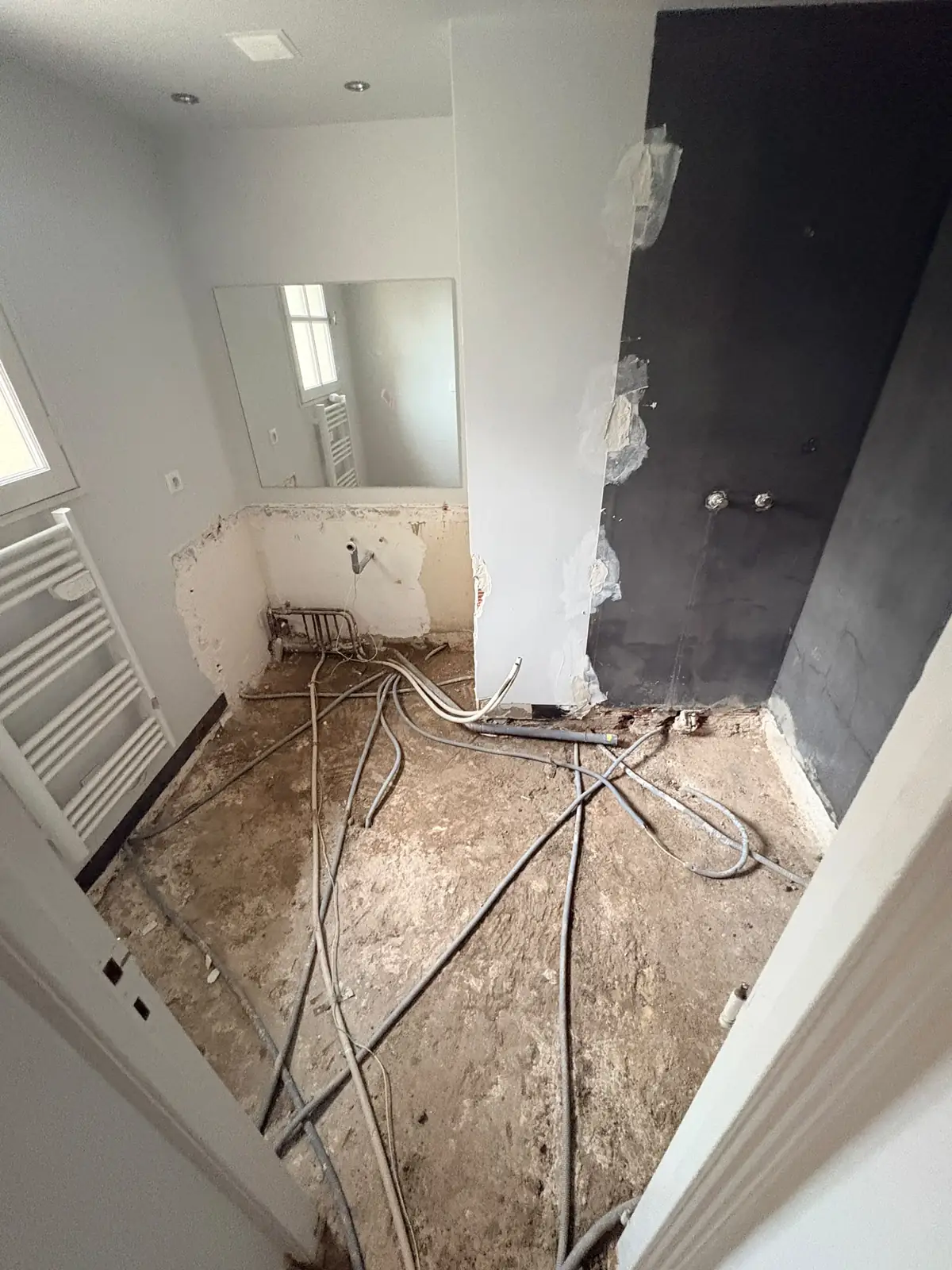 Pendant les travaux : sol décaissé et réseaux de plomberie en attente, avant la pose du carrelage