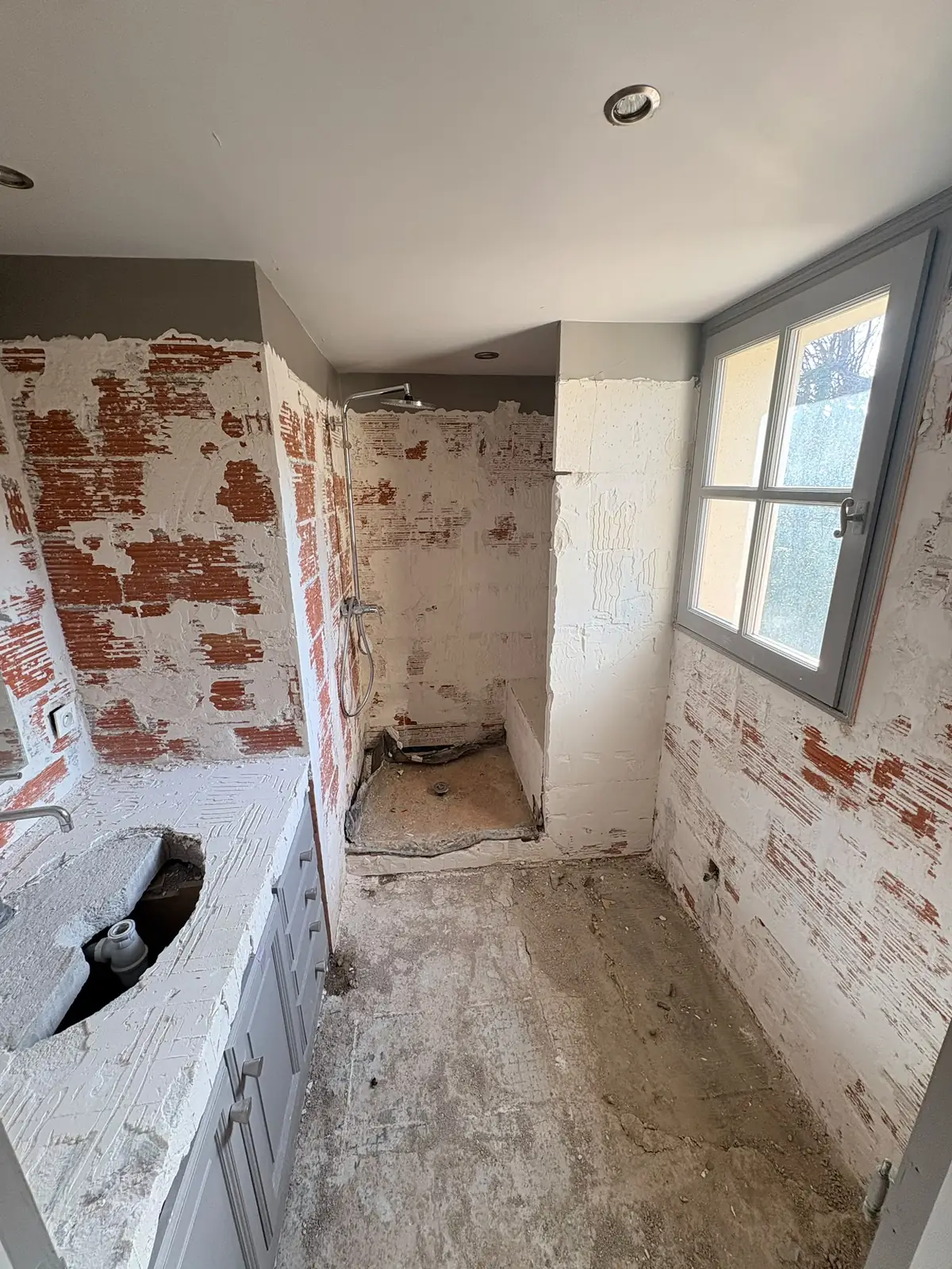 Pendant les travaux : anciens revêtements déposés, murs en briques et plan vasque mis à nu