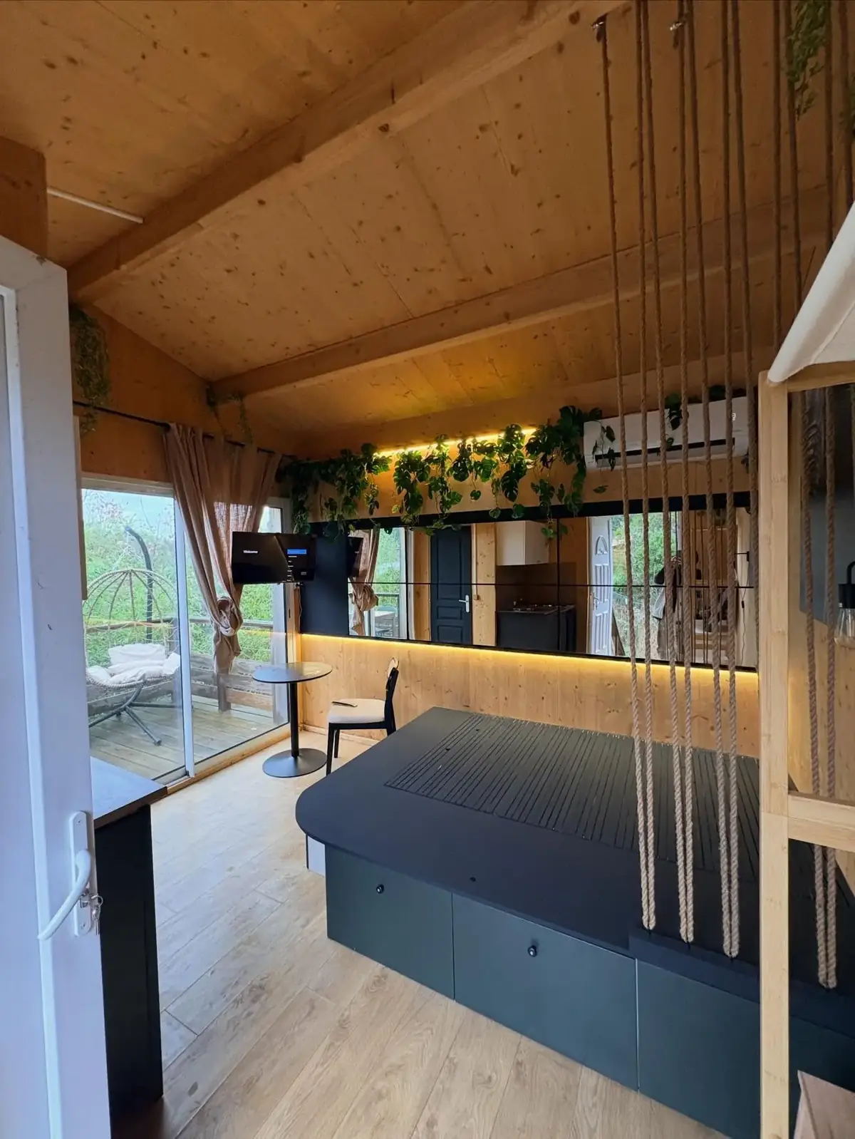 Studio rénové pour la location saisonnière à Bagnols-en-Forêt : lit estrade à rangements, murs en bois clair et miroirs rétroéclairés