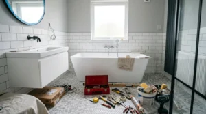 Salle de bain moderne carrelée blanc, baignoire et outils de rénovation au sol.
