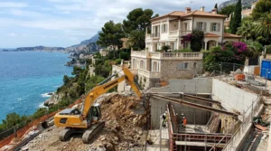 Pelle mécanique creusant sous une villa en bord de mer, cuvelage béton.