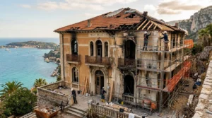 Villa de la Côte d’Azur endommagée, murs tachés, traces d’incendie, ouvriers réparant.